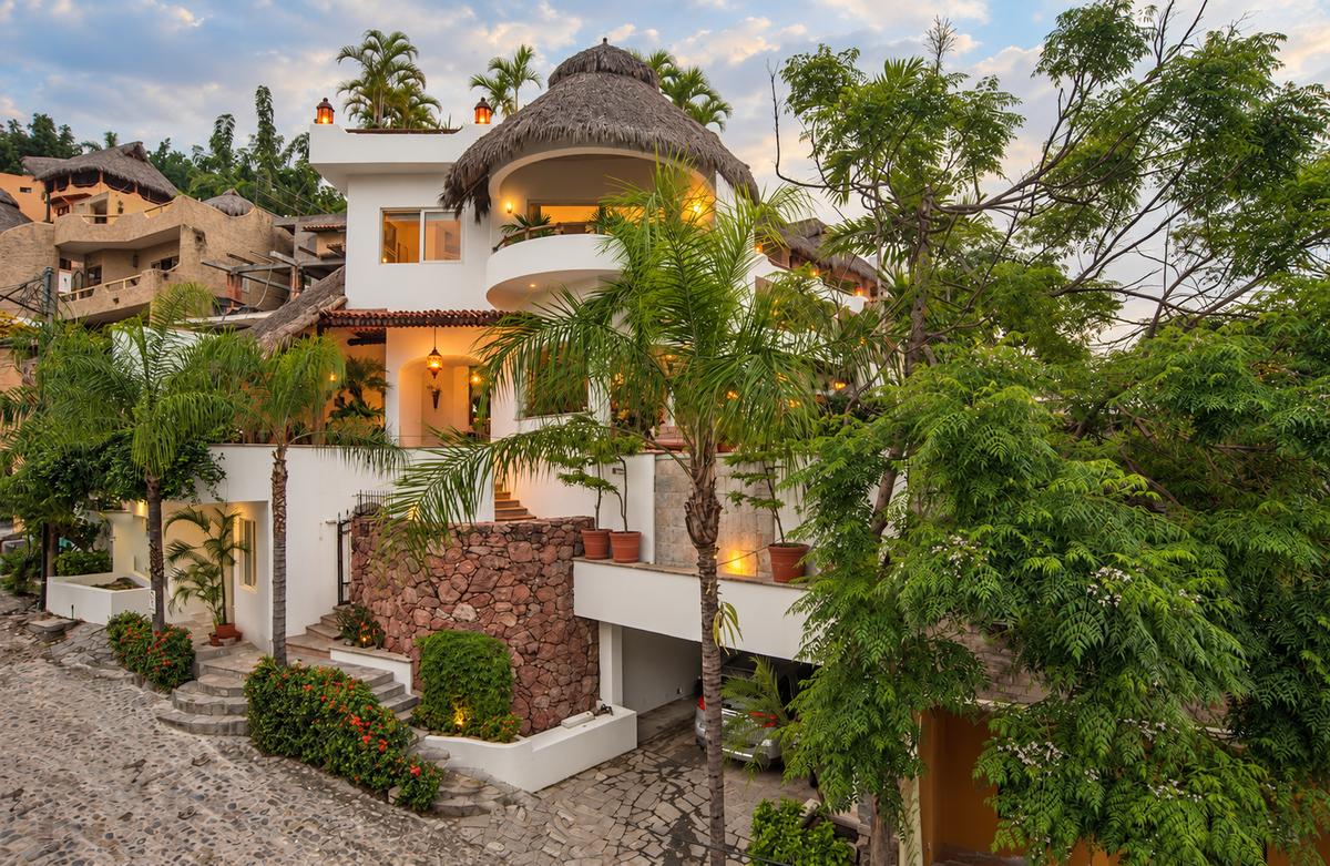 La casa entre palmeras, con su palapa en lo alto