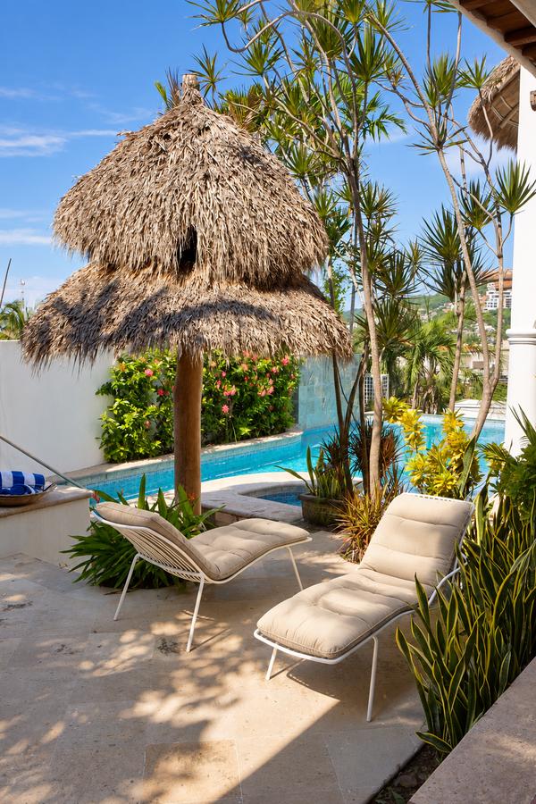 Camastros bajo una palapa junto a la alberca