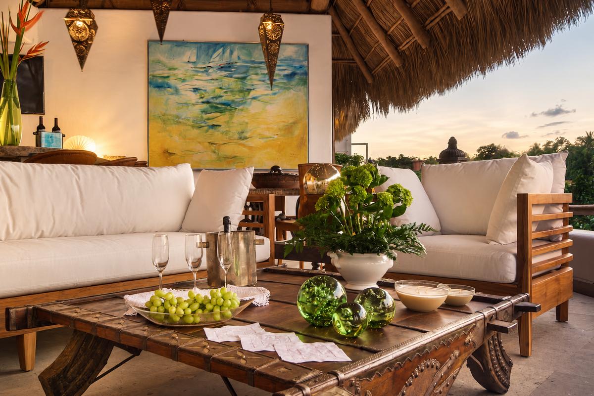 Sala bajo la palapa de la azotea, con uvas sobre la mesa